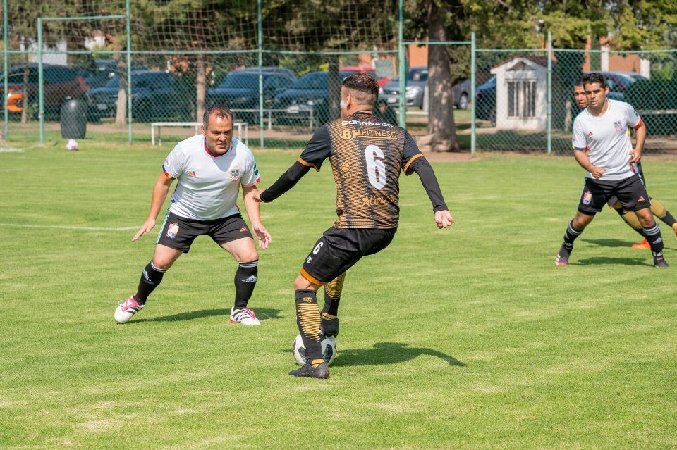 Adult men playing a friendly soccer game on a grassy field under clear skies. Adult men playing a friendly soccer game on a grassy field under clear skies.