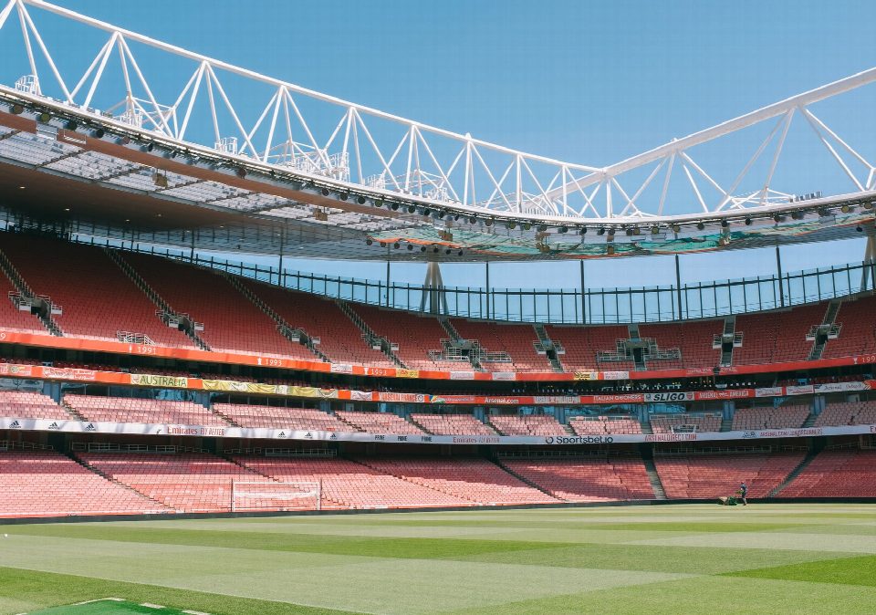 Wide view of Emirates Stadium's empty stands under a clear blue sky in London. Wide view of Emirates Stadium's empty stands under a clear blue sky in London.