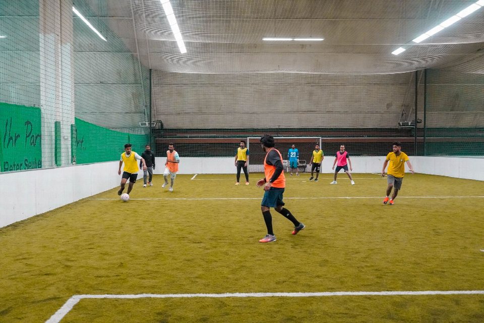 A lively indoor soccer game with diverse players actively engaging in the sport. A lively indoor soccer game with diverse players actively engaging in the sport.