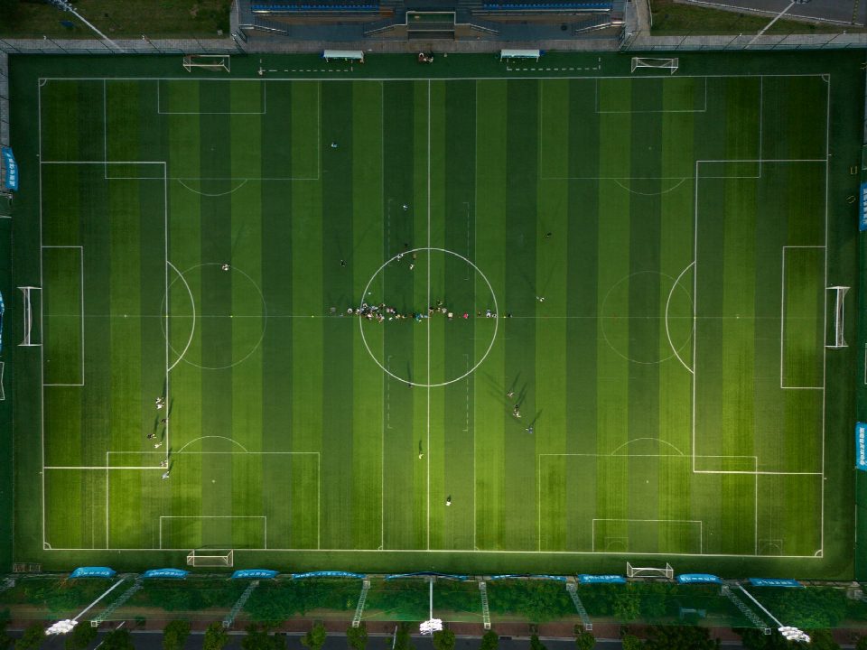 Top-down view of a soccer field with players during daytime. Top-down view of a soccer field with players during daytime.